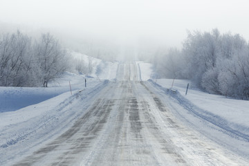 Remote frozen road in fog in winter