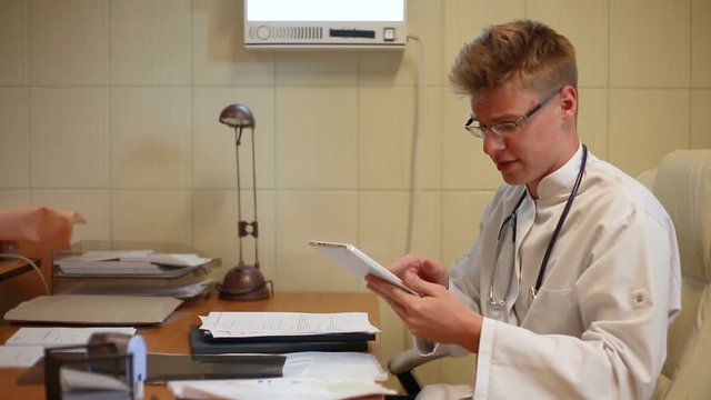 Doctor checking something on tablet and talking to the camera
