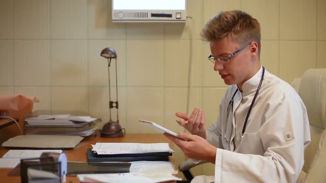 Doctor looks worried while checking results and talking to the camera

