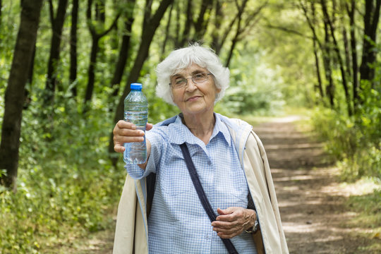 senior woman holding bottle of water in the green summer  park.Healthy living concept  