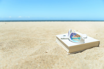 Sunglasses, book and phone on the beach