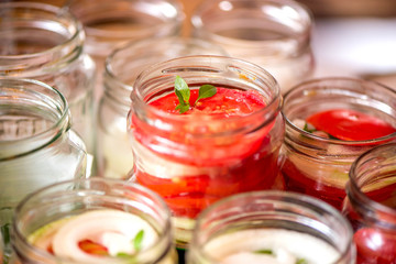 Fototapeta na wymiar Canning fresh tomatoes with onions for winter in jelly marinade. A shot of basil leaves on top of a red ripe tomato slices and onion rings being put in jar.