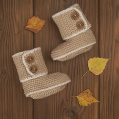 hand made crochet baby booties on wooden background, toned photo
