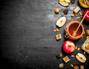 Honey background. Honey in pot with slices of ripe apples and nuts.