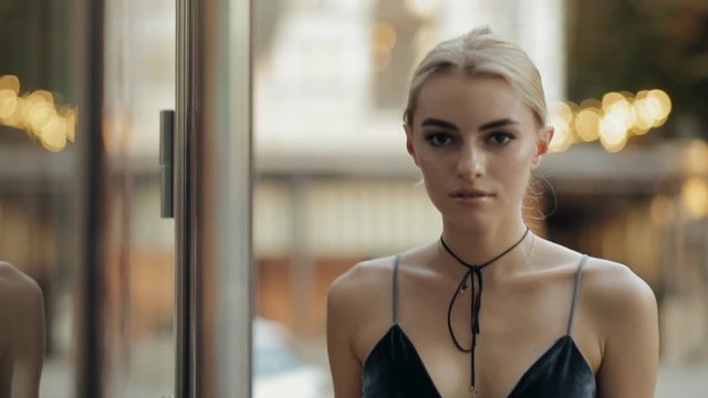 Fashion model walking on a city street in evening, slow motion