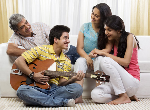Boy playing the guitar for his family 