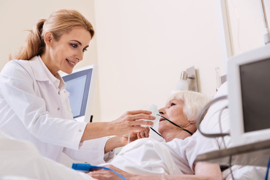 Neat competent woman putting an oxygen mask on her patient