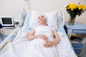 Obraz na płótnie Canvas Fragile elderly woman restoring her strength in the hospital