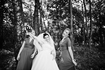 Gentle bride and beautiful bridesmaids are having great fun in the park on a sunny wedding day. Black and white photo.