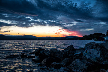 Large blocks of stones on the shore of the lake against the backdrop of a beautiful sunset