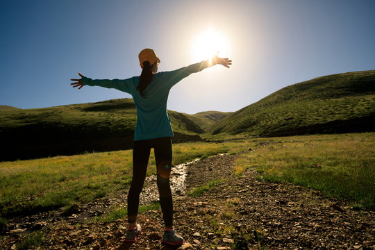 young woman open arms  in sunrise mountains
