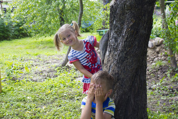 Girl and boy playing hide-and-seek. Boy close his eyes by hand