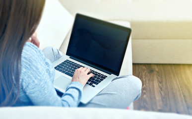 woman sitting back on sofa with laptop.