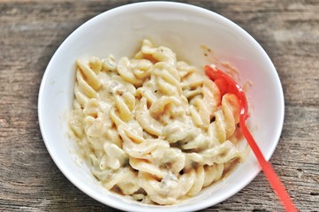 colored of macaroni in white bowl and red spoon on the wooden table.
