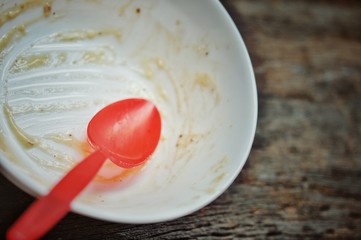 white bowl and red spoon after the finished the meal on the wooden table, dirty bowl