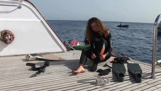 Beautiful model dress gear for diver on ship near water in Red Sea. Filming a movie. Young girl smiling at camera.