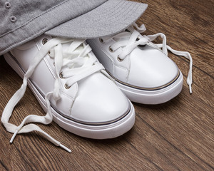 White sneakers with gray cap on dark wooden surface