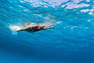 Fototapeta premium Female professional swimmer gushing through blue Red sea water with bubbles