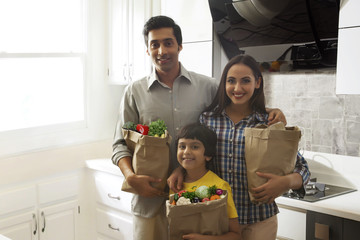 Family carrying bags of groceries in kitchen