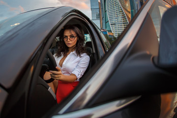 Business woman wearing red skirt sitting in a luxury car after work at evening