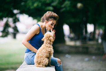 Portrait of beautiful young woman with her little red poodle puppy.