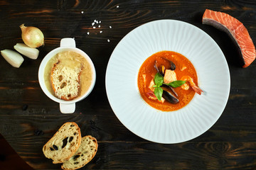Homemade seafood soup with tomato sauce and coconut milk on an old wood tray