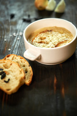 Broth with toasts of bread and black olives