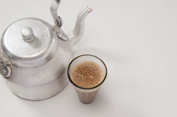 High angle view of chai in glass with an old fashioned kettle isolated over white background 