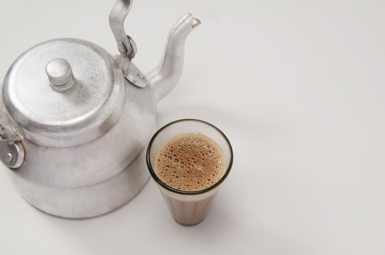 High Angle View Of Chai In Glass With An Old Fashioned Kettle Isolated Over White Background 