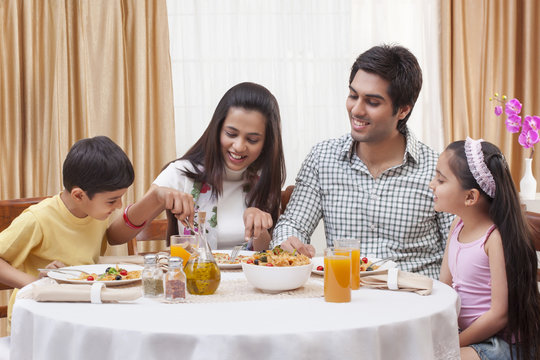 Happy Indian family having pizza together at restaurant 