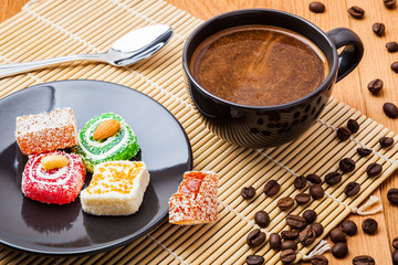 A cup of strong black coffee and a few pieces of traditional Turkish delight close-up