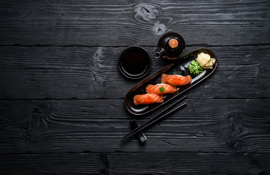 Japanese cuisine. Salmon sushi nigiri with soy sauce on a dark wooden background.