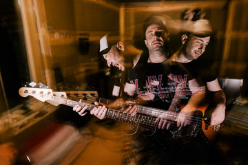 Naklejka premium Recording studio background. Music band rehearsal. Adult male guitarist portrait in garage, split personality, blurred motion