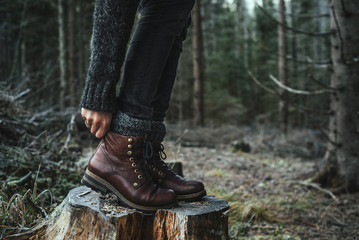 woman in boots standing on a stump