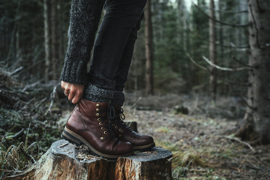woman in boots standing on a stump