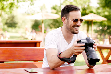 Portrait of bearded man holding dslr while sitting in cafe.