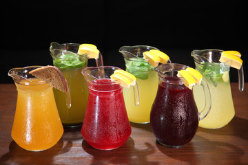 Lemonade in the jug and lemons with mint on the table indoor. Berry Lemonade. Quenching thirst and refreshing drinks. Cold lemonades. 