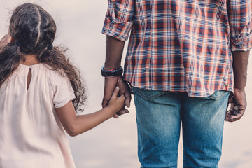 rear view of african american grandfather holding hands with granddaughter