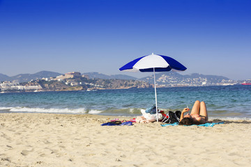 Ibiza sandy beach young girl under a umbrella