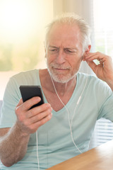 Portrait of mature man listening music with earphones, light effect