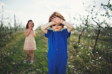 Naklejka premium little boy and girl in blooming garden