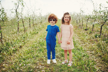 Fototapeta premium little boy and girl in blooming garden