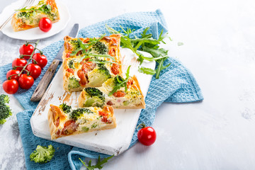 Delicious vegetarian homemade pie, Quiche with cherry tomatoes, broccoli and herbal cheese on old white cutting board. Healthy food concept. Copy space.