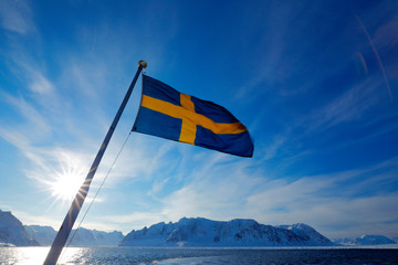 Sweden flag with blue sky. Rocky island with snow. White snowy mountain, blue glacier Iceberg twilight, ocean. Pink clouds with ice floe. Beautiful landscape. Land of ice. Cold blue water nature.