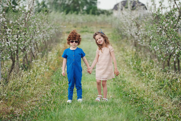 Obraz premium little boy and girl in blooming garden