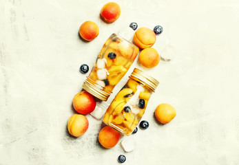 Summer cold fruit tae with apricot, blueberry and ice, food background, top view