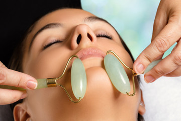 Facial beauty treatment with jade rollers. © karelnoppe
