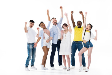 group of happy young multiethnic people triumphing and smiling at camera isolated on white