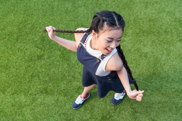 high angle view of beautiful smiling asian girl posing while standing on green grass