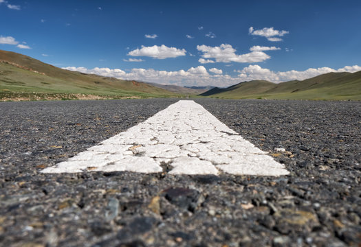 Wide-angle shot of empty road markings on asphalt in Mongolia between mongolian towns Tsagaannuur and Bayan-Olgii